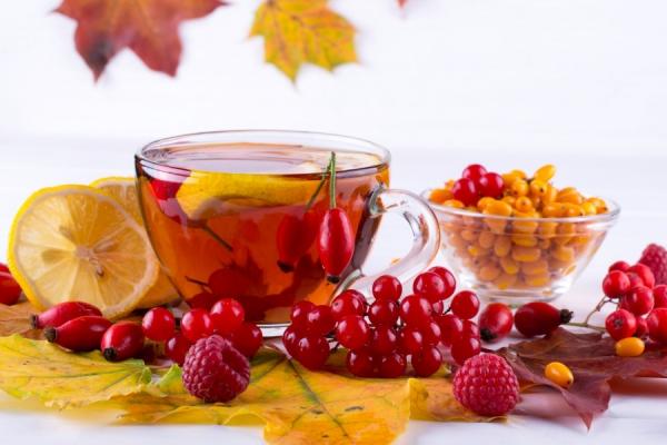 A cup of hot tea sits next to an assortment of berries